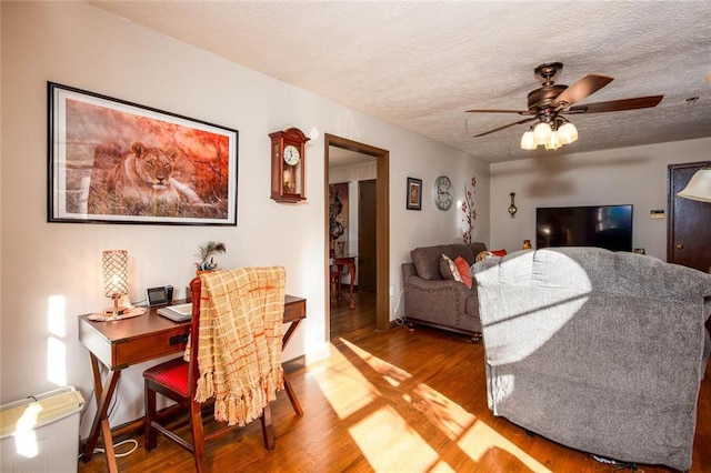 living room featuring ceiling fan, hardwood / wood-style floors, and a textured ceiling