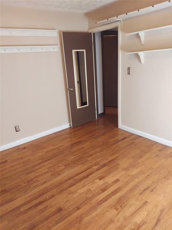 empty room with hardwood / wood-style floors and a textured ceiling