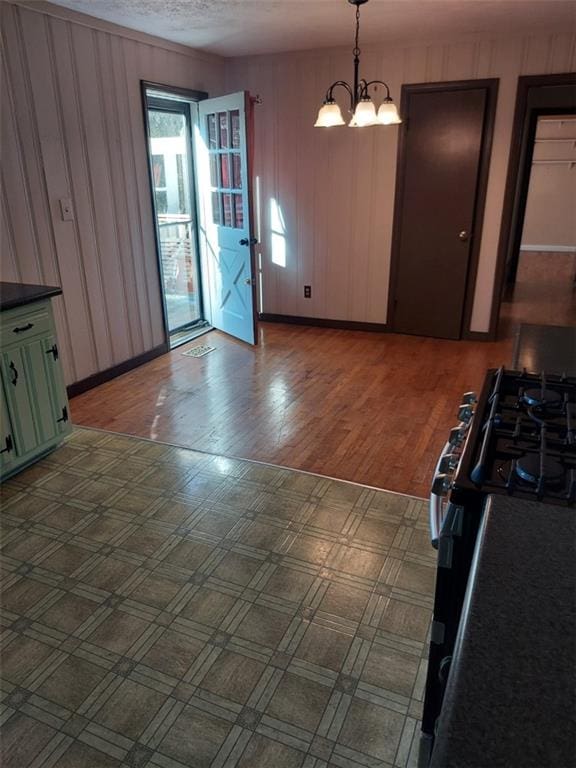 unfurnished dining area with hardwood / wood-style flooring, a textured ceiling, and a chandelier