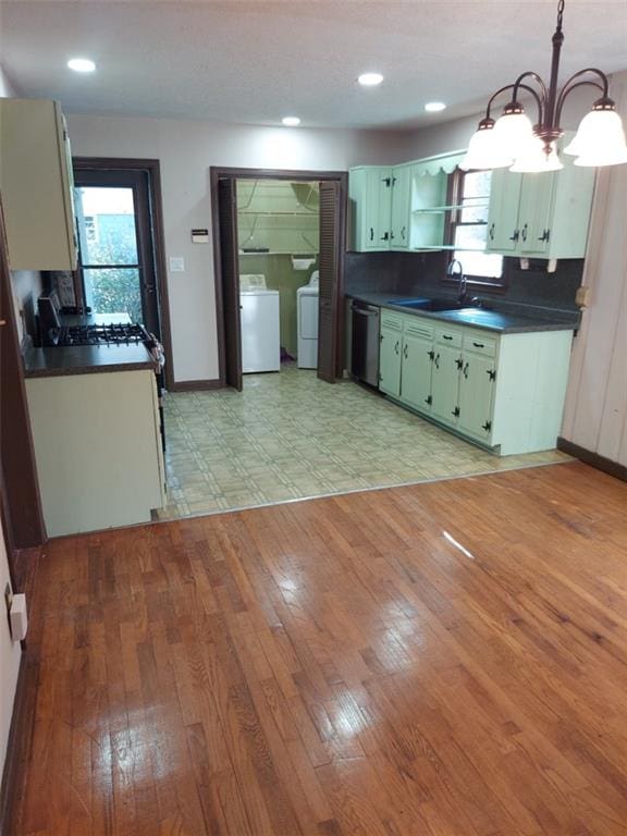 kitchen featuring washing machine and clothes dryer, sink, green cabinetry, hanging light fixtures, and dishwasher