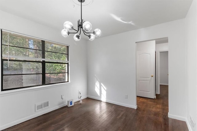 empty room featuring a notable chandelier and dark hardwood / wood-style flooring