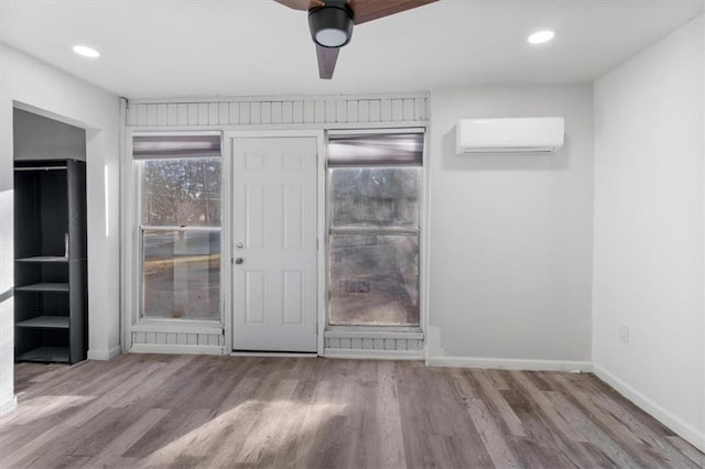 interior space featuring ceiling fan, a wall mounted air conditioner, and light wood-type flooring