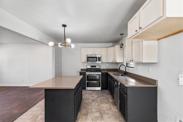 kitchen with a kitchen island, appliances with stainless steel finishes, pendant lighting, sink, and white cabinets