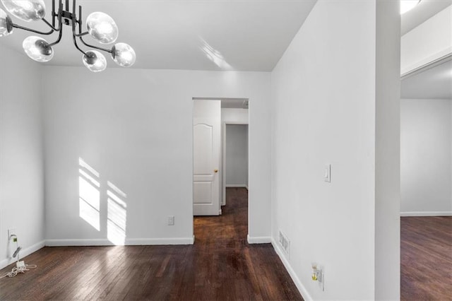 unfurnished room with dark hardwood / wood-style floors and a chandelier