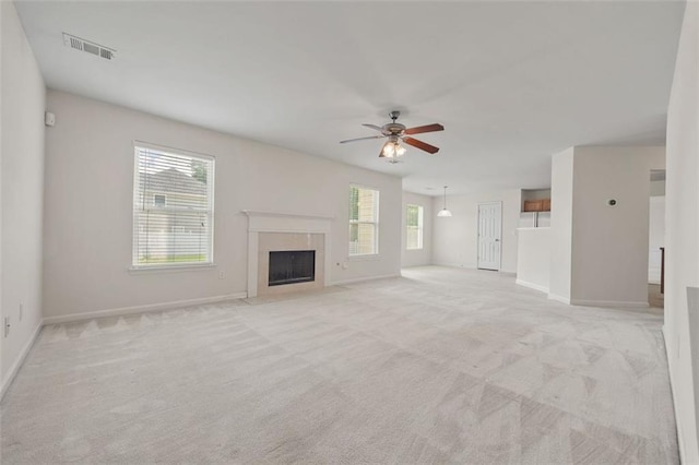 unfurnished living room featuring light colored carpet, plenty of natural light, ceiling fan, and a high end fireplace