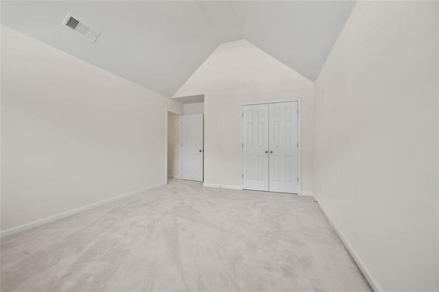 unfurnished bedroom with light colored carpet, lofted ceiling, baseboards, and a closet