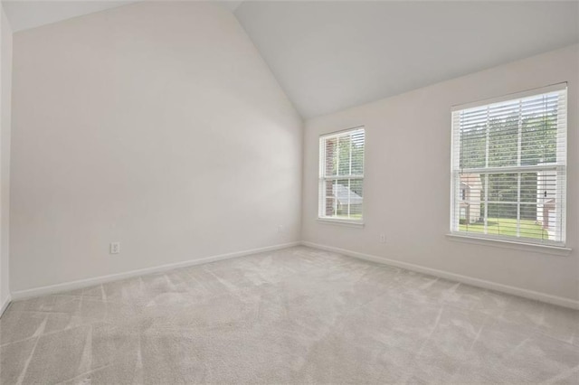 empty room with lofted ceiling, healthy amount of natural light, and light carpet