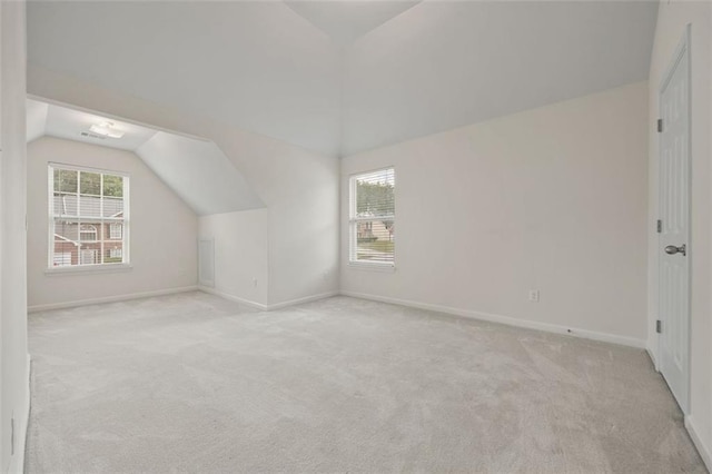 bonus room featuring lofted ceiling, light colored carpet, and baseboards