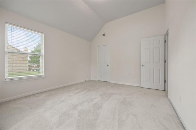 unfurnished bedroom with light carpet, lofted ceiling, and baseboards