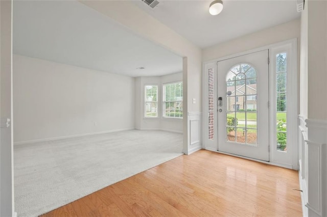 foyer with wood finished floors, baseboards, and carpet