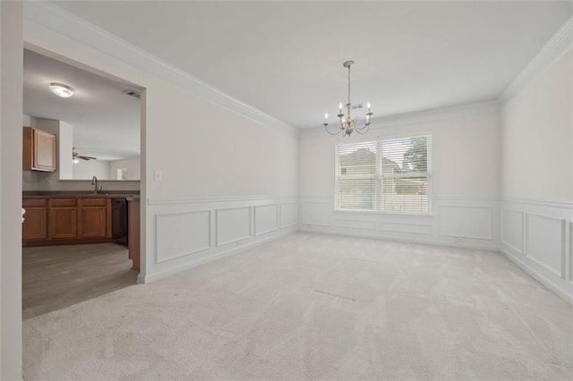 unfurnished dining area featuring a sink, a chandelier, ornamental molding, light carpet, and a wainscoted wall
