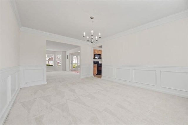 empty room with crown molding, a chandelier, a decorative wall, light colored carpet, and a wainscoted wall