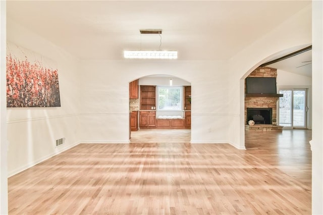 unfurnished living room with light wood-style floors, a wealth of natural light, a fireplace, and baseboards