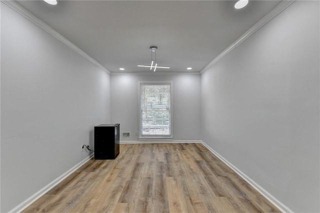 spare room featuring crown molding and light wood-type flooring