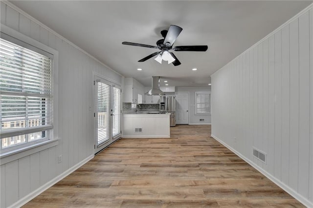 kitchen with exhaust hood, ceiling fan, white cabinetry, light hardwood / wood-style flooring, and ornamental molding