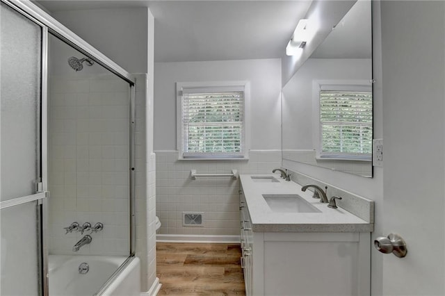 full bathroom with hardwood / wood-style floors, tile walls, shower / bath combination with glass door, toilet, and vanity