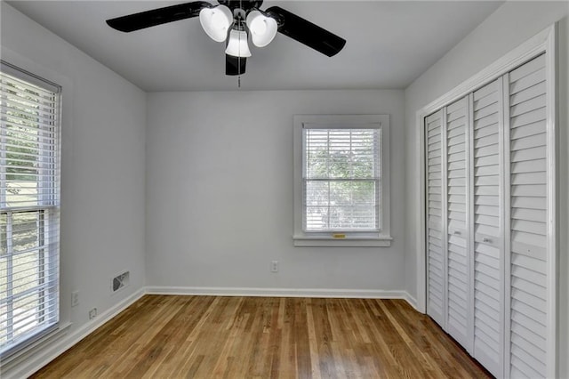 unfurnished bedroom featuring a closet, wood-type flooring, and multiple windows