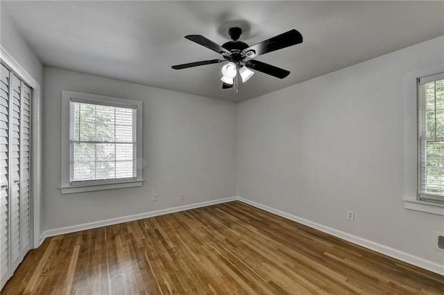 empty room featuring ceiling fan, hardwood / wood-style flooring, and a wealth of natural light