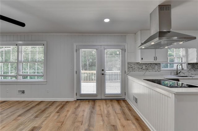 kitchen featuring a healthy amount of sunlight, sink, white cabinetry, light hardwood / wood-style floors, and wall chimney exhaust hood