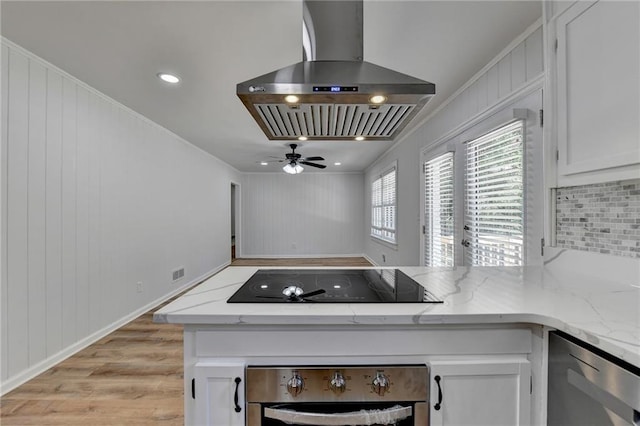 kitchen featuring light wood-type flooring, island exhaust hood, white cabinetry, stainless steel appliances, and light stone counters