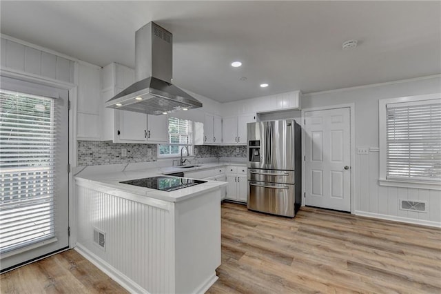 kitchen with wall chimney range hood, white cabinets, light hardwood / wood-style floors, and stainless steel fridge with ice dispenser