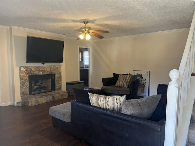 living room featuring crown molding, ceiling fan, a fireplace, wood finished floors, and a textured ceiling