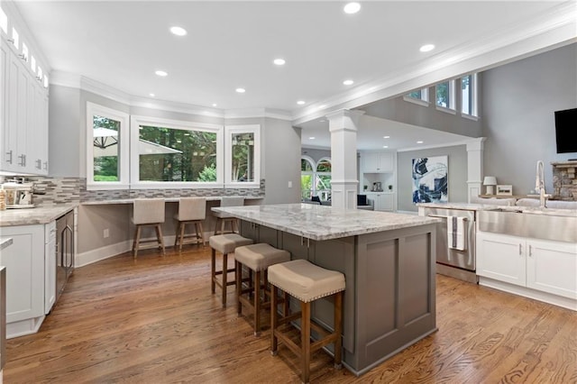 2510 Wood Creek Ct, Dacula, GA 30019 - kitchen featuring dishwasher, a sink, ornate columns, a kitchen island, and white cabinets