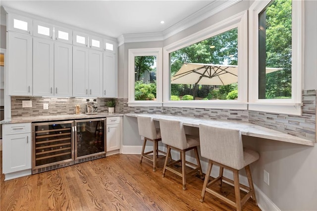 2510 Wood Creek Ct, Dacula, GA 30019 - indoor bar with wine cooler, tasteful backsplash, light wood-type flooring, and crown molding