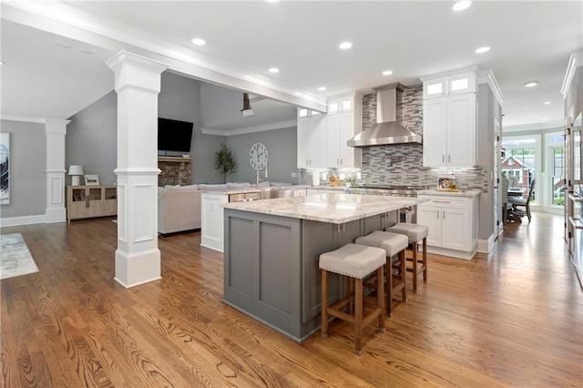 2510 Wood Creek Ct, Dacula, GA 30019 - kitchen featuring wall chimney exhaust hood, open floor plan, wood finished floors, a peninsula, and decorative backsplash