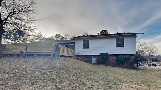 rear view of property featuring central AC unit and a lawn