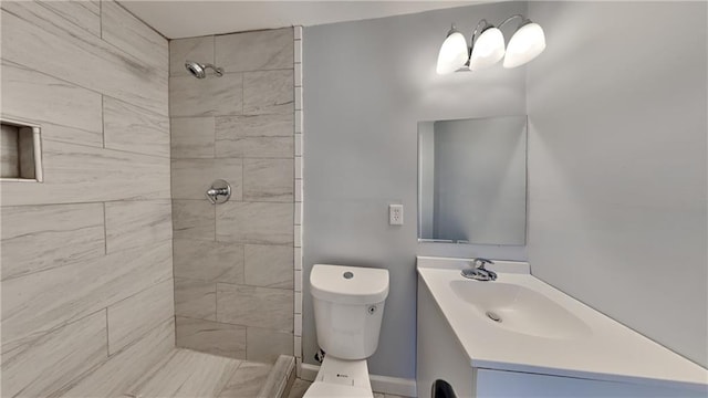 bathroom featuring vanity, toilet, and a tile shower