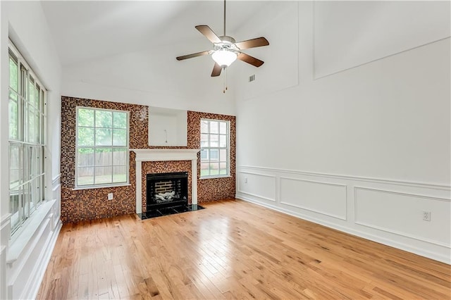 2520 Laurel Cir NW, Atlanta, GA 30311 - unfurnished living room with light wood finished floors, a decorative wall, a ceiling fan, a tiled fireplace, and wainscoting