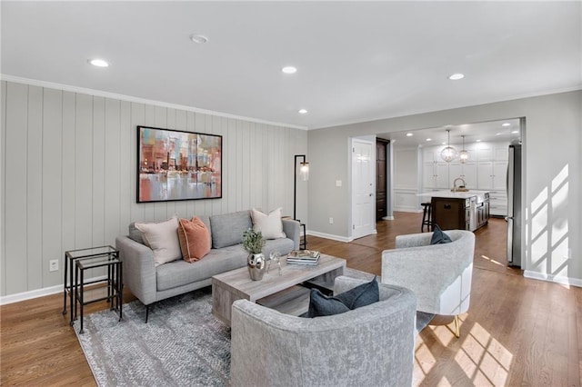 living room with sink, hardwood / wood-style flooring, and ornamental molding