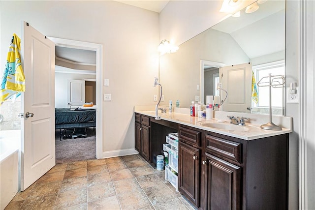 bathroom with vaulted ceiling, a bathtub, and vanity