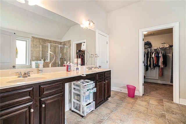 bathroom featuring vanity, lofted ceiling, and a shower with door