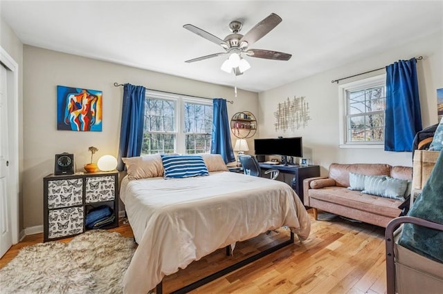 bedroom featuring light wood-style flooring, multiple windows, and ceiling fan