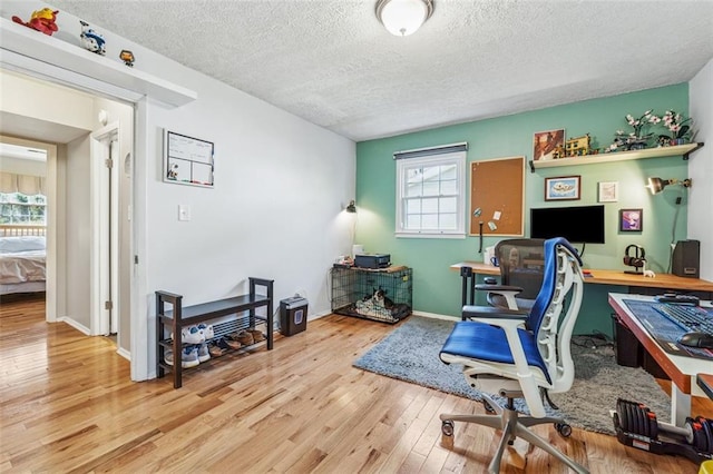 home office featuring a textured ceiling, baseboards, and hardwood / wood-style flooring