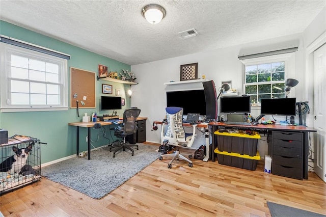 home office featuring visible vents, baseboards, a textured ceiling, and wood finished floors