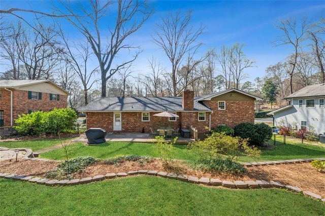 rear view of house featuring a lawn, fence, brick siding, a chimney, and a patio area