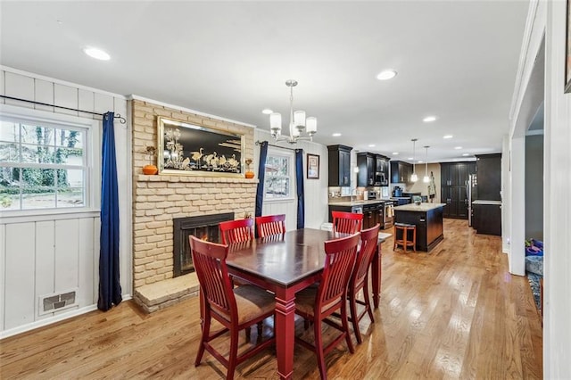 dining area with a fireplace, visible vents, a chandelier, and light wood-type flooring