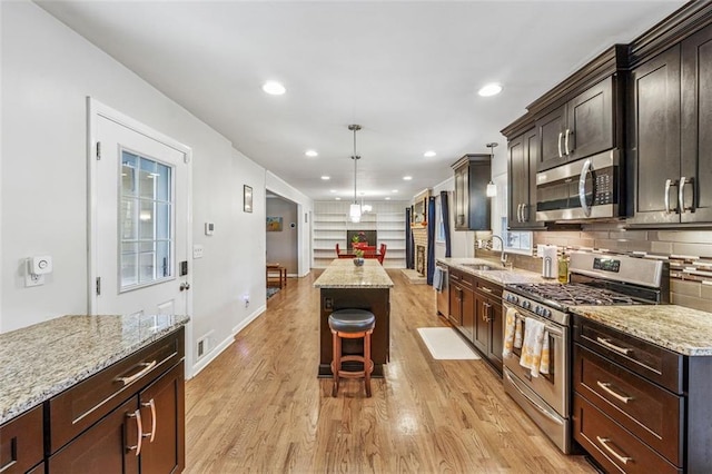 kitchen featuring backsplash, light stone counters, recessed lighting, light wood-style flooring, and stainless steel appliances