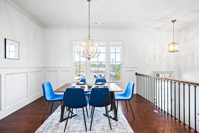 dining space with ornamental molding, a decorative wall, and an inviting chandelier