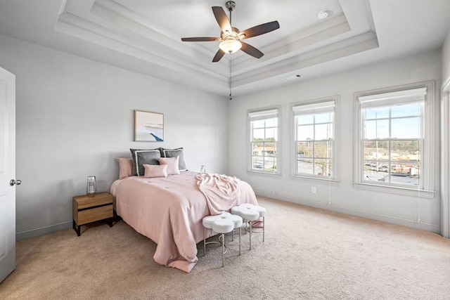 bedroom with baseboards, a tray ceiling, multiple windows, and light colored carpet