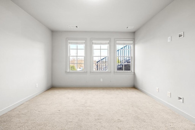 empty room with light colored carpet, visible vents, and baseboards