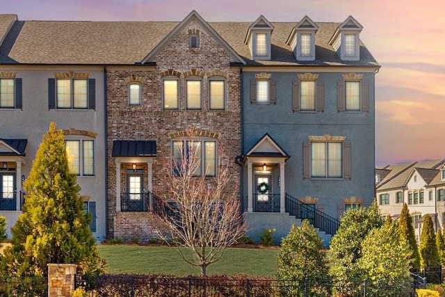 view of front of home featuring fence, a lawn, and brick siding