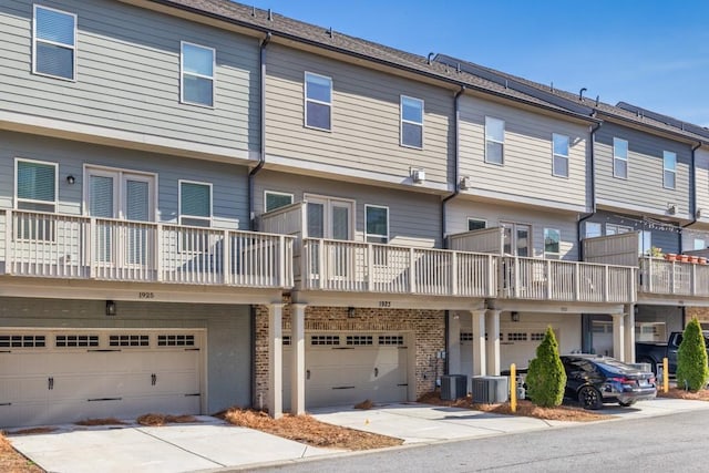 exterior space with central air condition unit, an attached garage, and brick siding