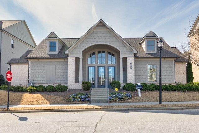 view of front of property featuring a shingled roof, french doors, and brick siding