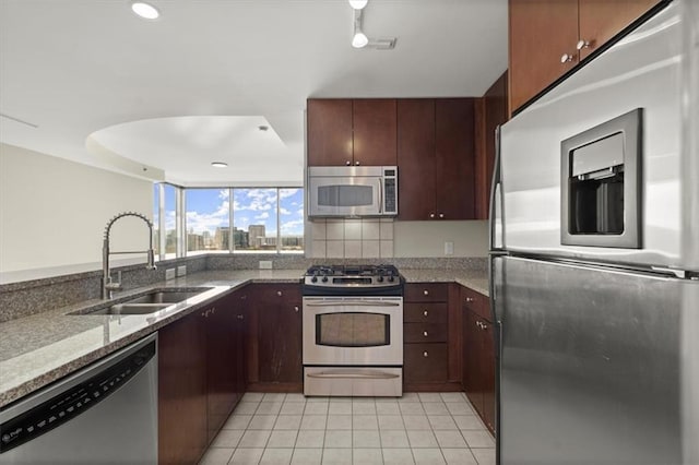 kitchen featuring light tile patterned flooring, stainless steel appliances, a sink, light stone countertops, and tasteful backsplash