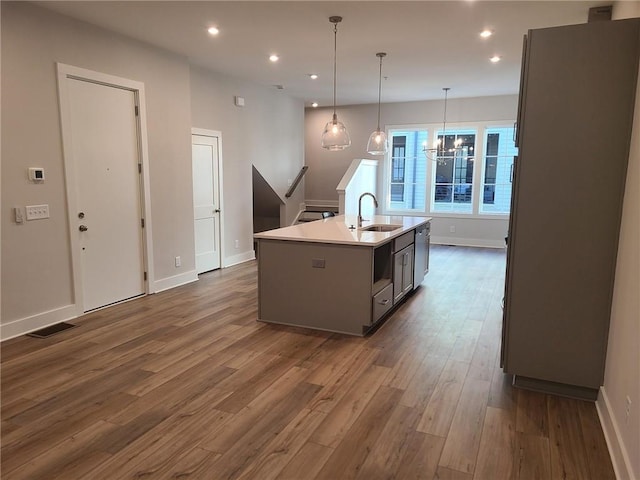 kitchen featuring gray cabinetry, sink, dark hardwood / wood-style flooring, decorative light fixtures, and a kitchen island with sink