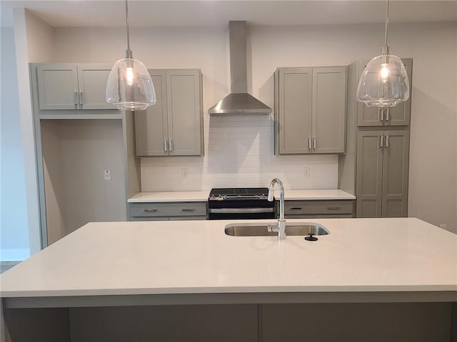 kitchen with sink, decorative light fixtures, gray cabinets, and wall chimney range hood